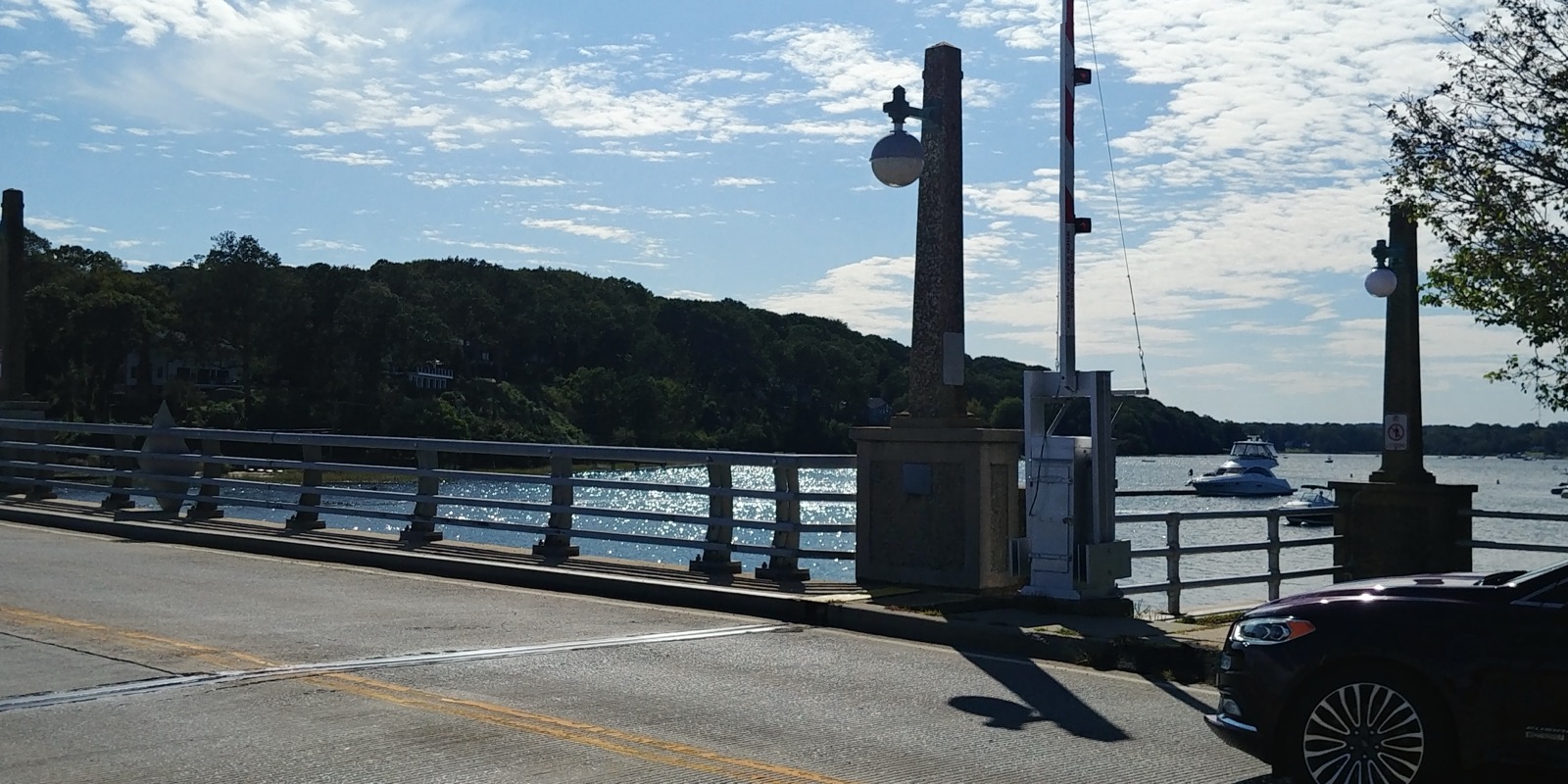 Bayville Bridge with stone obelisk lamp posts over calm water and a moored boat