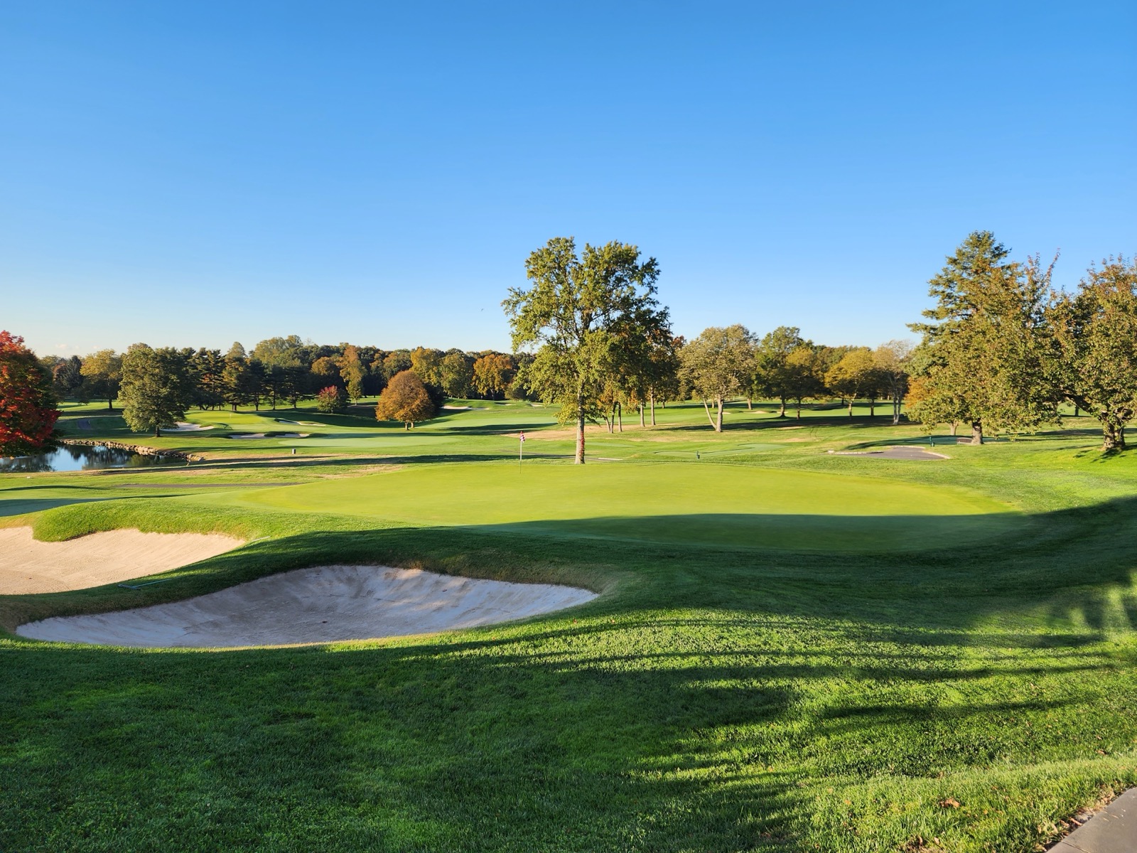 Glen Head Country Club fairway and green with sand bunker under clear blue sky