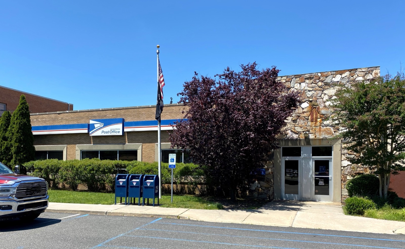 Glen Head United States Postal Service branch exterior with flag and blue mailboxes