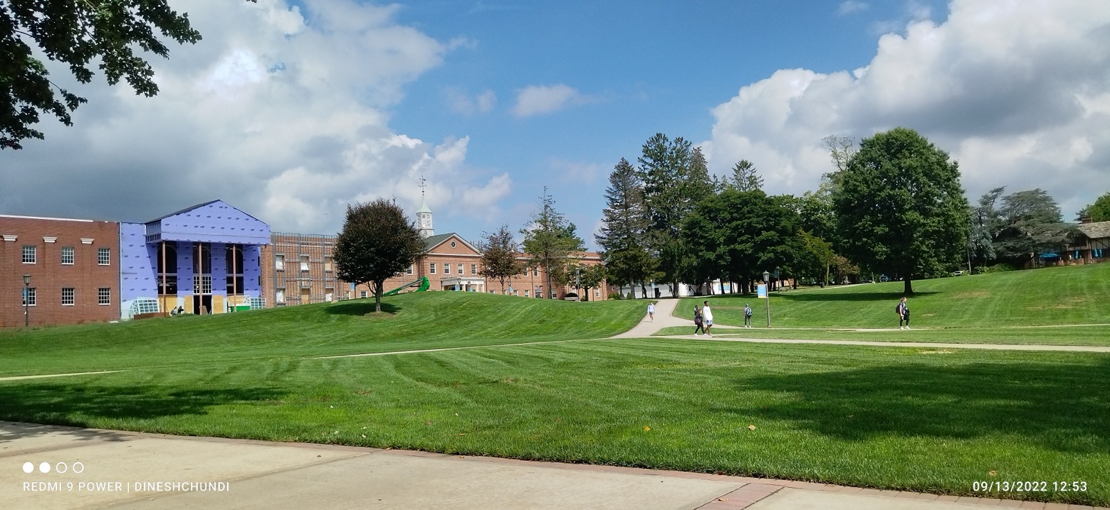 Wide campus lawn with brick academic buildings and trees on a sunny day