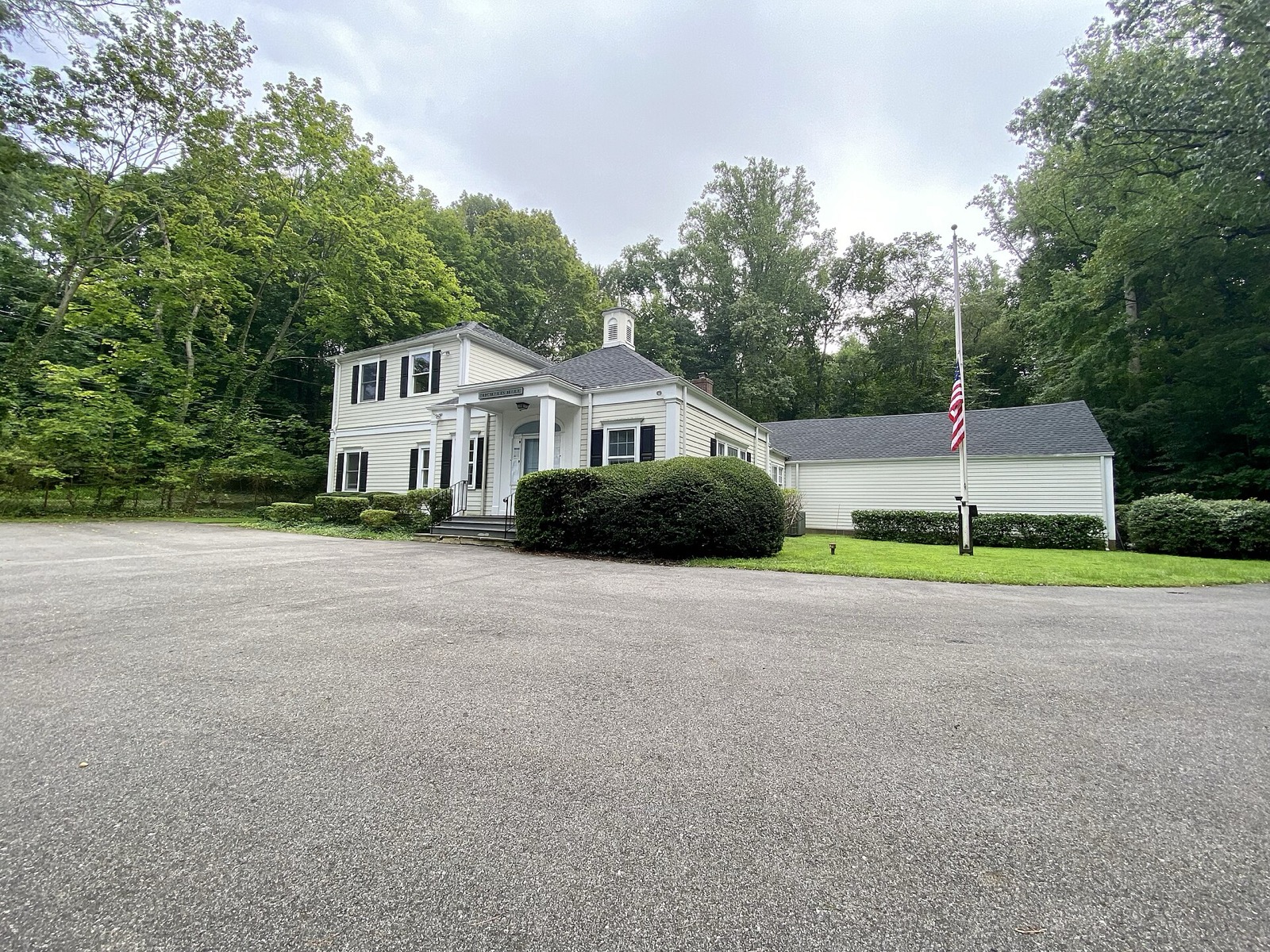 Lattingtown Village Hall, a low building on a tree-lined village road