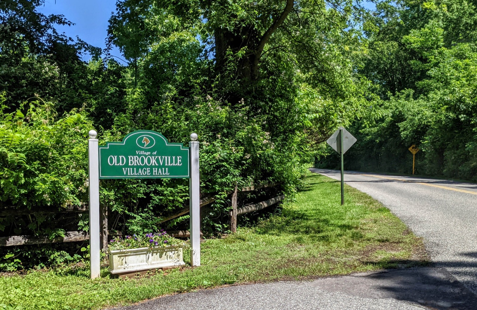Green Village of Old Brookville Village Hall sign beside a country road