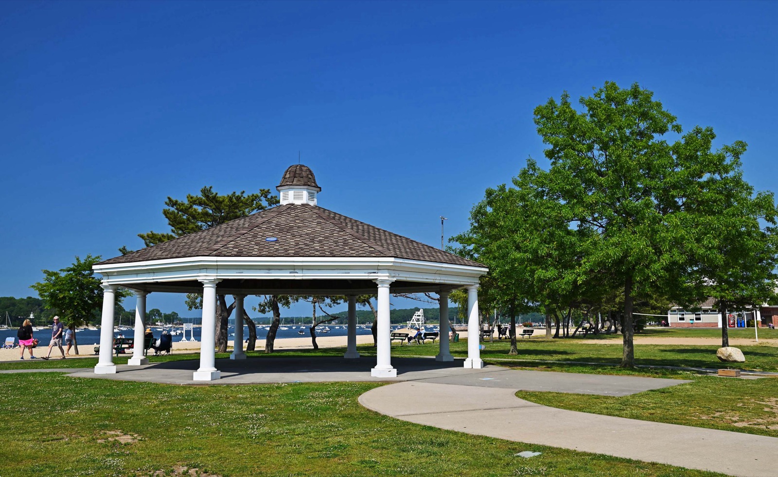 White columned gazebo with shingled roof on grass beside the Oyster Bay waterfront