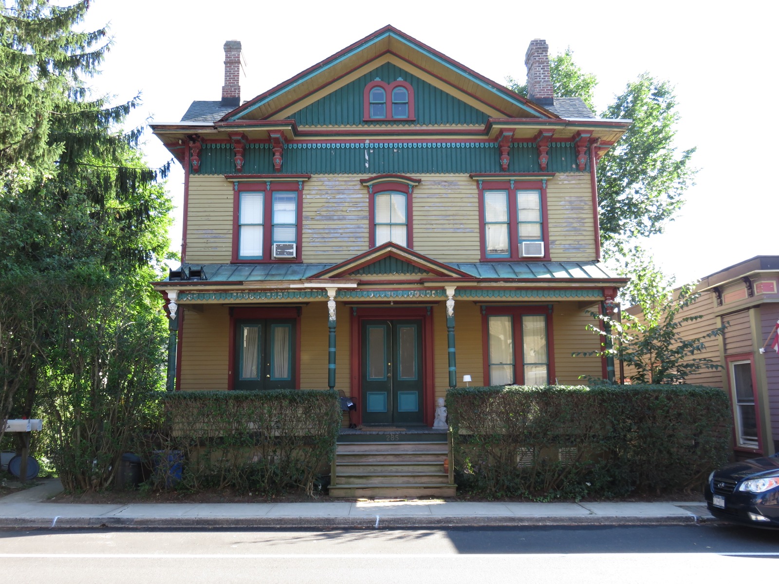 Two-story yellow Victorian house with green and red trim and a front porch, on Sea Cliff Avenue in Sea Cliff
